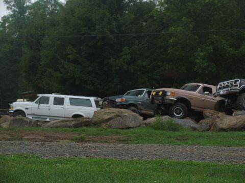 1995 Ford C-350 (Centurion Conversions) - Several off-road vehicles, including a white SUV and a tan truck, are positioned on large rocks.