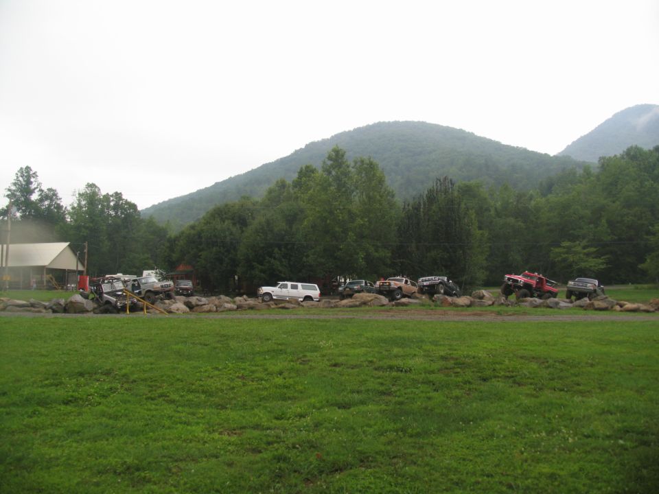 Several off-road vehicles are parked on rocks with a mountain in the background