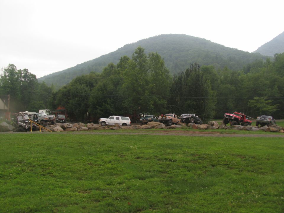 Multiple off-road vehicles navigating a rocky obstacle course with a mountain backdrop