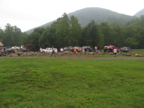 1995 Ford C-350 (Centurion Conversions) - Off-road vehicles and spectators gather at a rocky obstacle course with a mountainous backdrop.