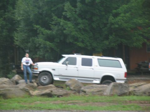 1995 Ford C-350 (Centurion Conversions) - A white extended SUV is parked on rocks with a person standing beside it.