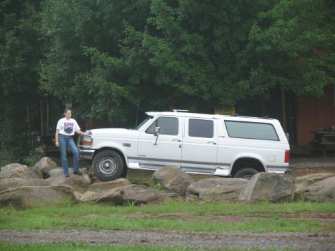 1995 Ford C-350 (Centurion Conversions) - A white 1995 Ford C-350 Centurion Conversions extended SUV is parked on large rocks, with a person standing next to it.