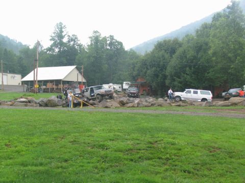 1995 Ford C-350 (Centurion Conversions) - Several off-road vehicles are seen navigating a challenging rocky terrain in an outdoor setting.