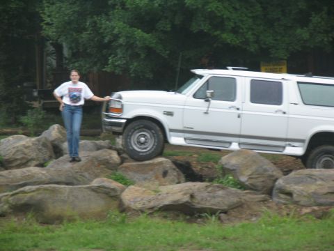 1995 Ford C-350 (Centurion Conversions) - A woman poses next to a white extended cab pickup truck that is parked on a rocky incline.