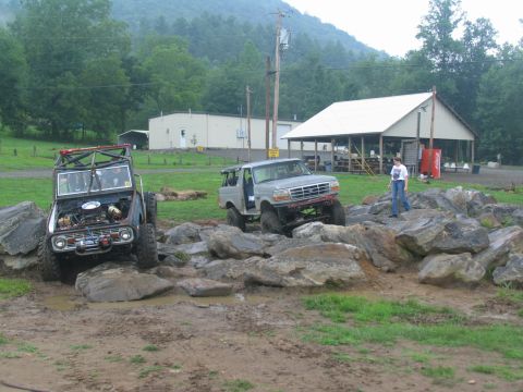 1995 Ford C-350 (Centurion Conversions) - Two modified Broncos tackle a challenging rock crawling course, one with its hood up.
