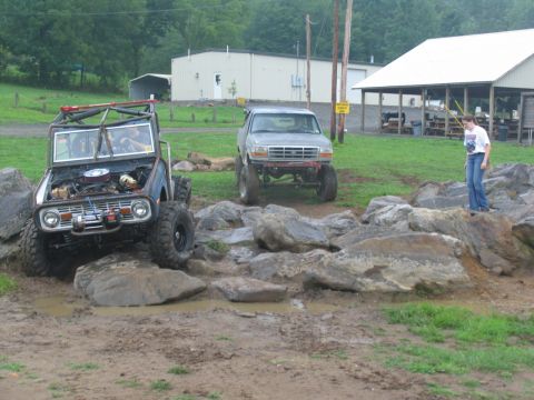 1995 Ford C-350 (Centurion Conversions) - Two vehicles tackle a rocky obstacle course with mud and puddles.