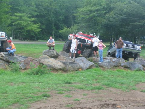 1995 Ford C-350 (Centurion Conversions) - Several people observe modified trucks navigating a rocky terrain.