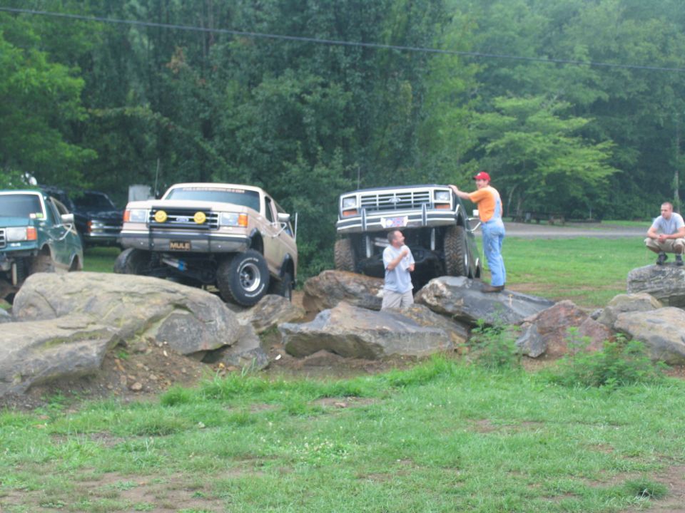 Tan lifted truck with yellow fog lights and "MULE" plate, on rocks