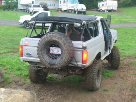 1995 Ford C-350 (Centurion Conversions) - Lifted Ford Bronco with a soft top and spare tire on the rear, parked in a muddy area.