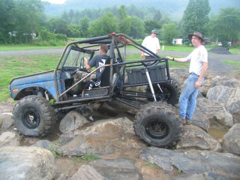 1995 Ford C-350 (Centurion Conversions) - A heavily modified off-road vehicle navigates a rocky terrain with two spectators observing.