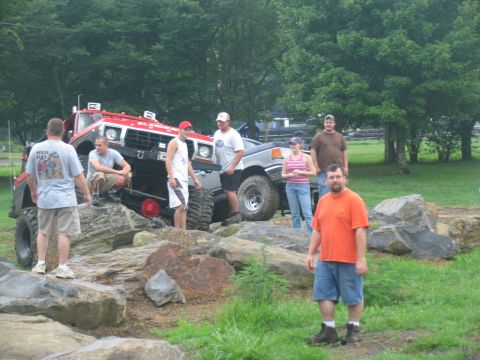 1995 Ford C-350 (Centurion Conversions) - Several people gather around a modified off-road truck navigating a rocky terrain.