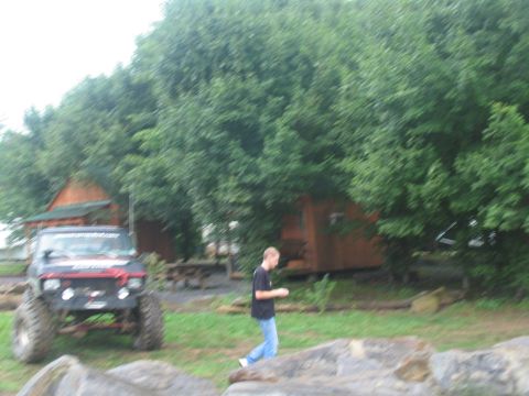 1995 Ford C-350 (Centurion Conversions) - Modified off-road truck with large tires parked in a grassy area near cabins.