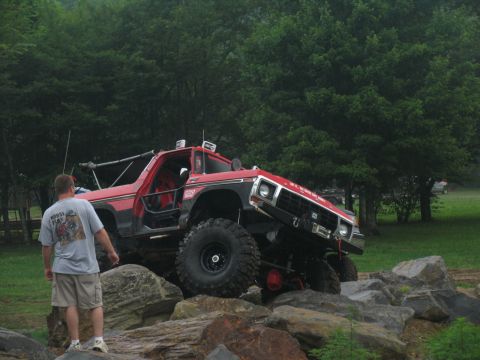 1995 Ford C-350 (Centurion Conversions) - Modified red truck with off-road tires is shown on a rocky terrain.