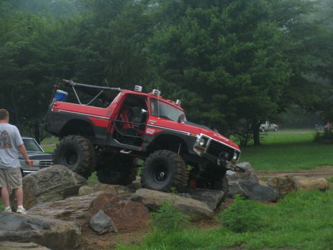 1995 Ford C-350 (Centurion Conversions) - Modified red Ford Bronco navigating a challenging rock obstacle course.