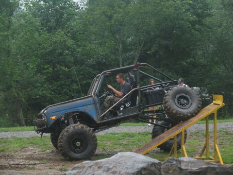 1995 Ford C-350 (Centurion Conversions) - A modified off-road buggy navigates a yellow ramp during an outdoor event.