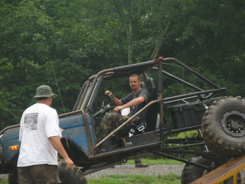 1995 Ford C-350 (Centurion Conversions) - A man sits in the driver's seat of a heavily modified off-road buggy with a prominent roll cage and large tires.