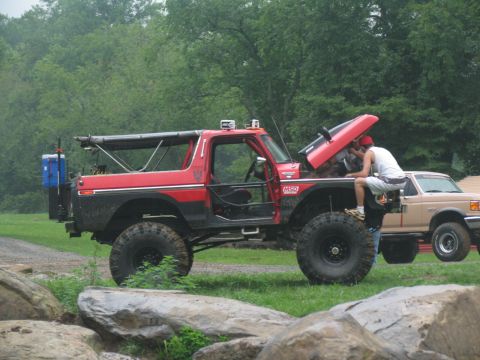 1995 Ford C-350 (Centurion Conversions) - Two trucks are parked outdoors, one with its hood up while someone works on the engine.