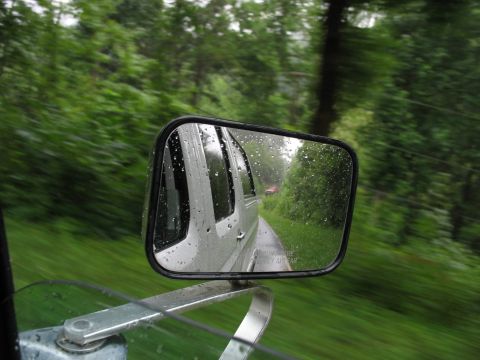 1995 Ford C-350 (Centurion Conversions) - View from inside a vehicle on a rainy day, looking at the side mirror which reflects another vehicle on the road.