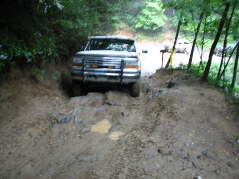 1995 Ford C-350 (Centurion Conversions) - Ford C-350 navigating a challenging muddy and rocky off-road trail.