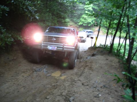 1995 Ford C-350 (Centurion Conversions) - A Ford F-Series truck navigates a muddy trail with another vehicle following behind.