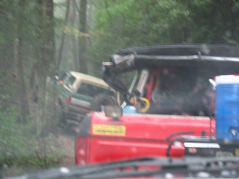 1995 Ford C-350 (Centurion Conversions) - Two off-road vehicles navigate a challenging path through a dense, green forest.