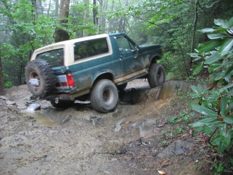 1995 Ford C-350 (Centurion Conversions) - This green SUV, likely a Ford Bronco from the mid-1990s, tackles a challenging off-road course.