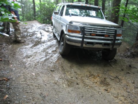 1995 Ford C-350 (Centurion Conversions) - White 1995 Ford C-350 (Centurion Conversions) navigates a challenging muddy path in the woods.