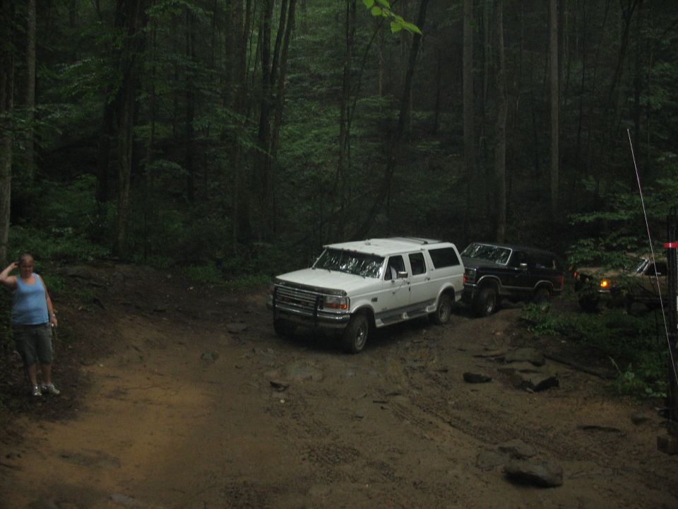 White 1995 Ford C-350 Centurion Conversions SUV on muddy forest road