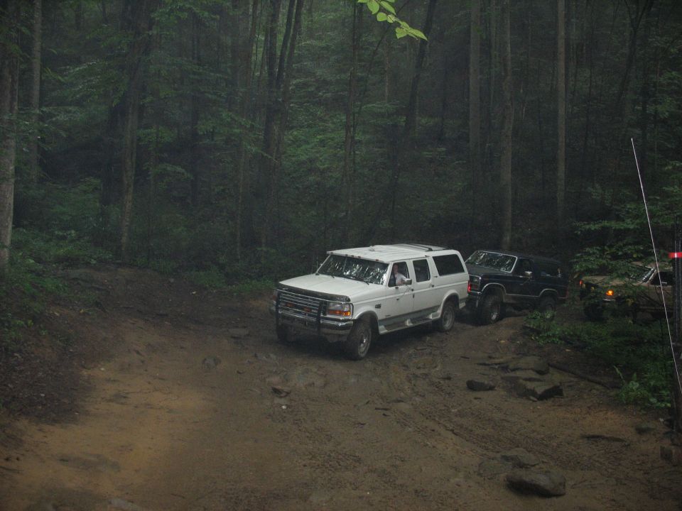 1995 Ford C-350 (Centurion Conversions) and two other SUVs on a muddy forest road
