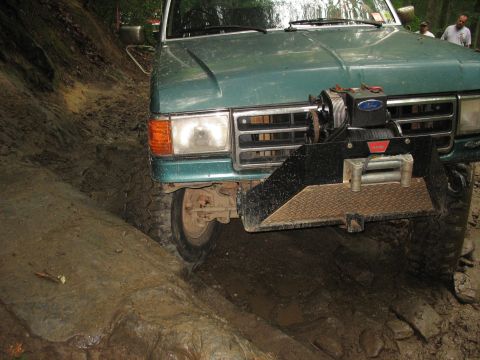 1995 Ford C-350 (Centurion Conversions) - A 1995 Ford C-350 (Centurion Conversions) equipped with a winch navigates a challenging muddy off-road course.