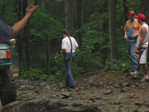 1995 Ford C-350 (Centurion Conversions) - A green SUV is partially visible on a rough, wooded trail with people standing nearby.