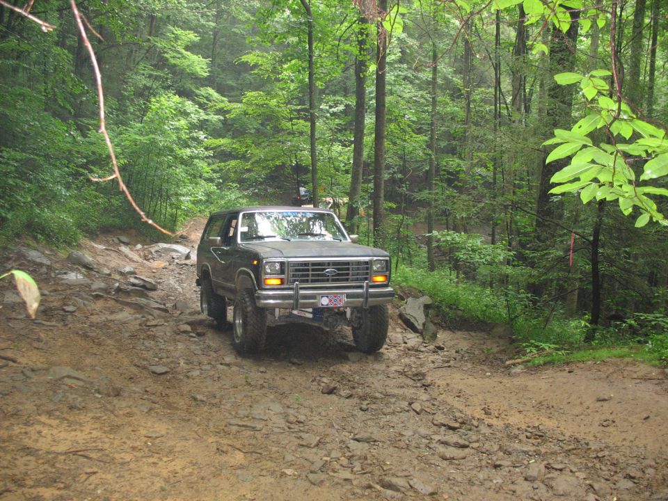 Dark SUV on muddy trail. License plate visible