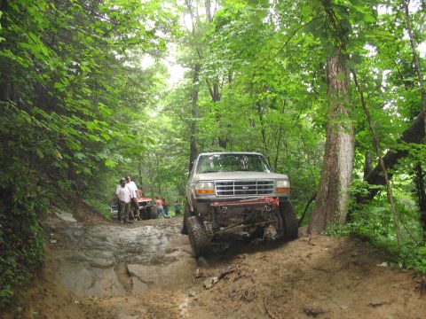 1995 Ford C-350 (Centurion Conversions) - A modified Ford F-Series truck tackles a challenging off-road course with other vehicles nearby.