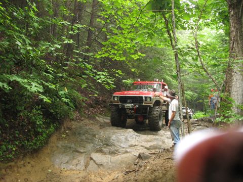 1995 Ford C-350 (Centurion Conversions) - Off-road pickup truck navigating a challenging trail through a wooded area.