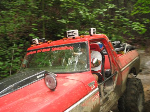 1995 Ford C-350 (Centurion Conversions) - A red pickup truck with "Southern Off-Road Specialists" on the windshield drives on a muddy trail.
