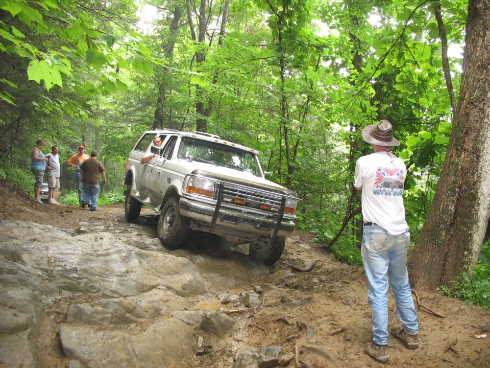White Ford Bronco navigating rocky off-road trail. Appears to be a 1992 model
