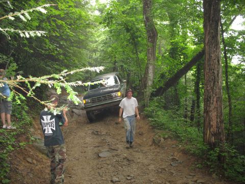 1995 Ford C-350 (Centurion Conversions) - A 1995 Ford C-350 (Centurion Conversions) navigates a challenging off-road path in a wooded area.