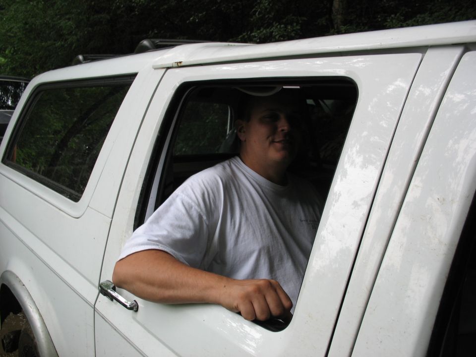 White SUV with a man leaning out the window. The vehicle appears to be from the early to mid-1990s