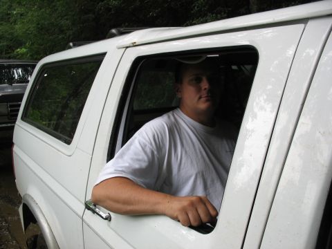 1995 Ford C-350 (Centurion Conversions) - A man sits in the driver's seat of a white SUV, with another vehicle partially visible to the left.