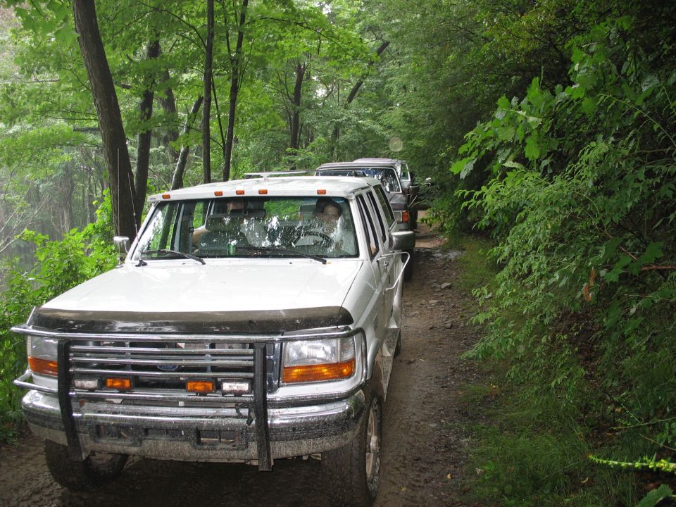 1995 Ford C-350 (Centurion Conversions) front view, part of a line of white SUVs on a muddy dirt road