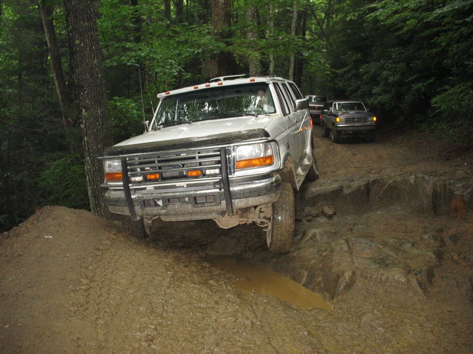 White 1995 Ford C-350 (Centurion Conversions) truck driving through mud
