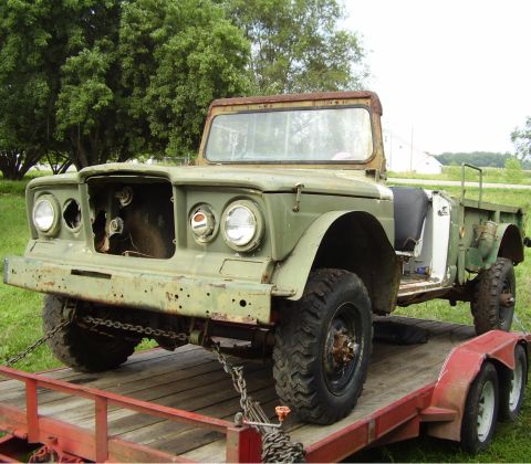 1968 Jeep J-20 - This 1968 Jeep J-20 truck is seen on a trailer, showing its olive green exterior and open bed.