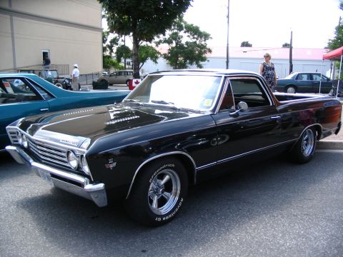 1993 Ford Taurus - A black 1967 El Camino pickup truck is parked next to a teal car at an outdoor car show.