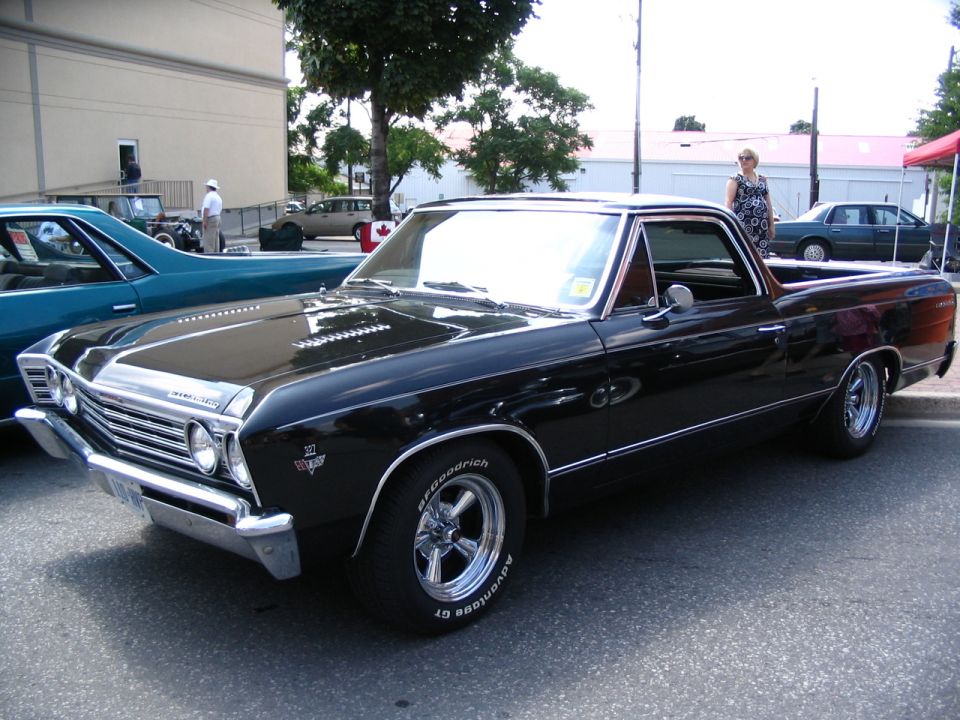 Black 1967 El Camino pickup truck parked next to a teal car