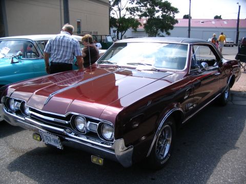 1993 Ford Taurus - A classic maroon Oldsmobile Cutlass Supreme is displayed at a car show, with another vintage car beside it.