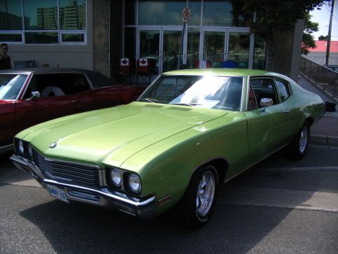 1993 Ford Taurus - A vintage lime green coupe is displayed at a car show, parked beside a red vehicle.