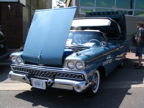 1993 Ford Taurus - A classic blue convertible is displayed with its hood and trunk open, revealing its engine and interior.