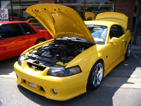 1993 Ford Taurus - Yellow Ford Mustang with its hood and trunk open, parked at an outdoor event.