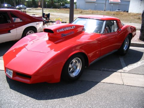 1993 Ford Taurus - A bright red Chevrolet Corvette, modified with a prominent hood scoop, is parked at a car show.