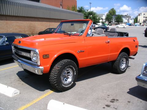 1993 Ford Taurus - Orange 1972 Chevrolet K5 Blazer convertible pickup truck seen at a car show.